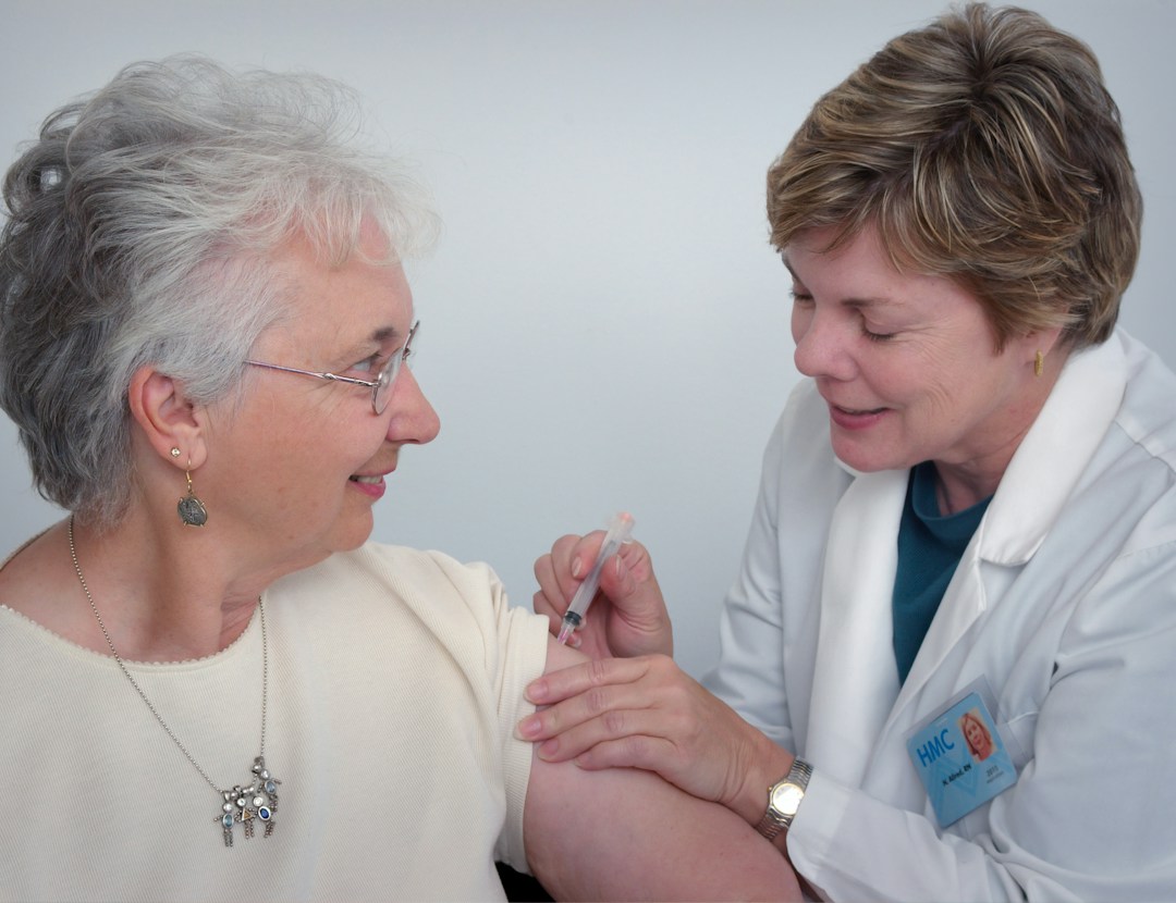 A healthcare professional administering a hyaluronic acid injection to a patient's knee.